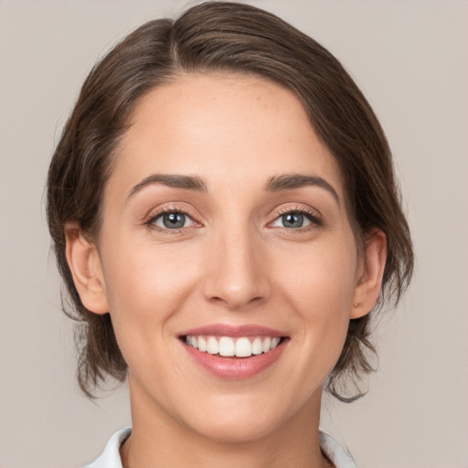 Joyful white young-adult female with medium  brown hair and grey eyes