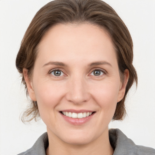 Joyful white young-adult female with medium  brown hair and grey eyes