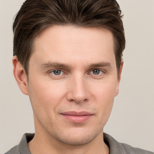 Joyful white young-adult male with short  brown hair and grey eyes