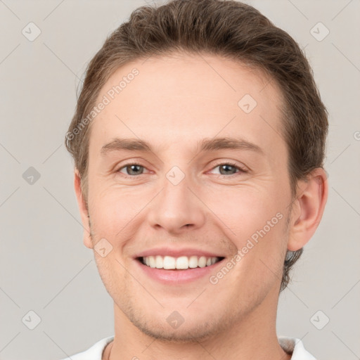 Joyful white young-adult male with short  brown hair and grey eyes