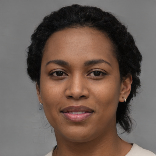 Joyful black young-adult female with short  black hair and brown eyes