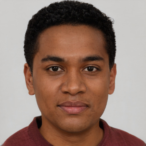 Joyful black young-adult male with short  brown hair and brown eyes