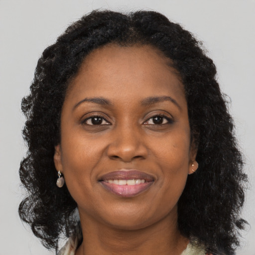 Joyful black young-adult female with long  brown hair and brown eyes
