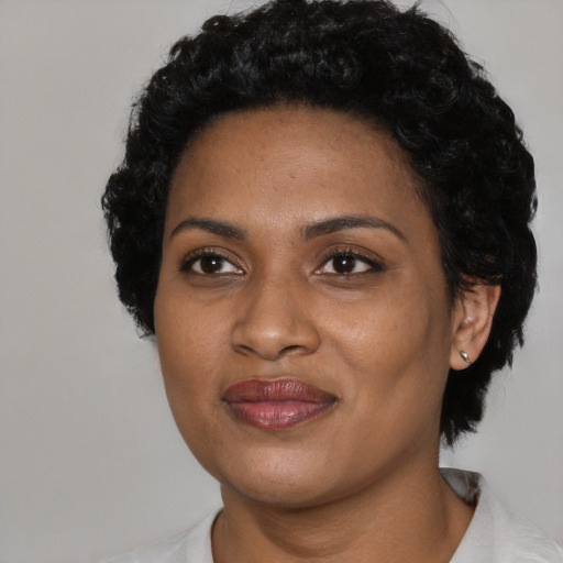 Joyful black young-adult female with short  black hair and brown eyes