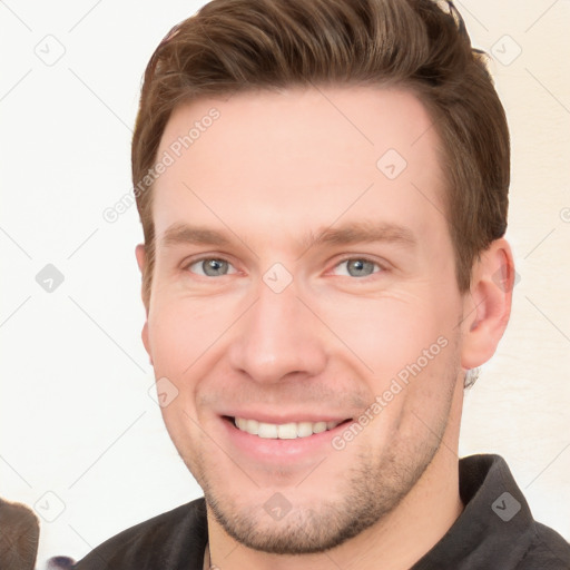 Joyful white young-adult male with short  brown hair and grey eyes