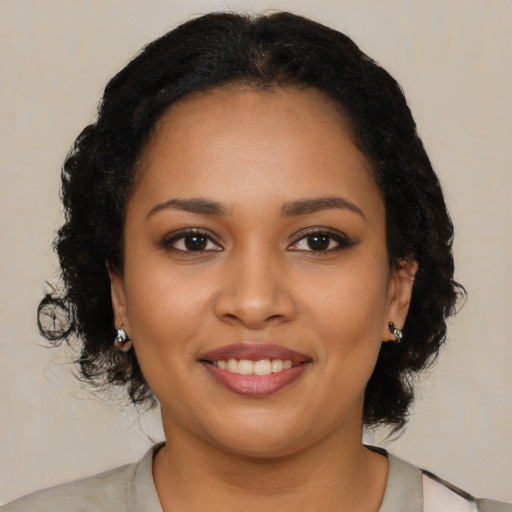 Joyful black young-adult female with long  black hair and brown eyes