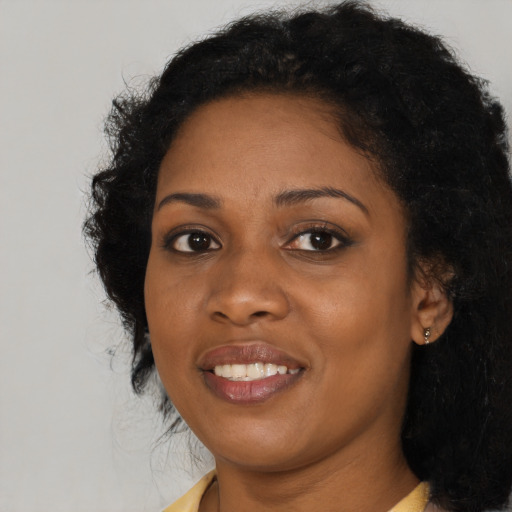 Joyful black young-adult female with long  black hair and brown eyes