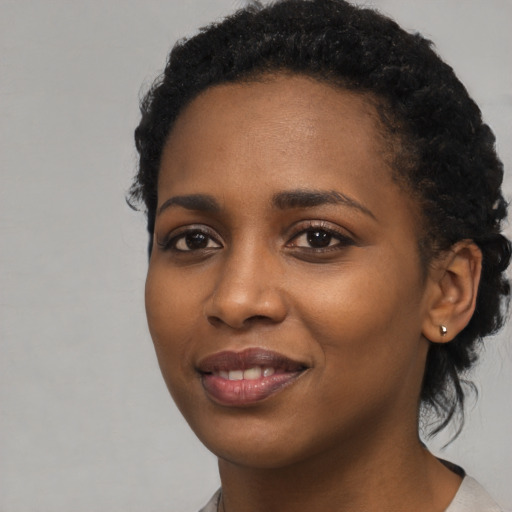Joyful black young-adult female with short  black hair and brown eyes