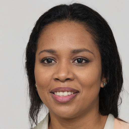 Joyful black adult female with long  brown hair and brown eyes