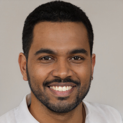 Joyful black young-adult male with short  black hair and brown eyes