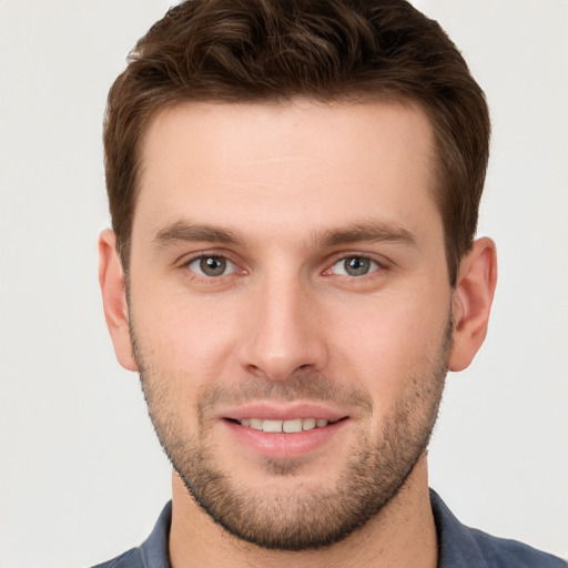 Joyful white young-adult male with short  brown hair and grey eyes