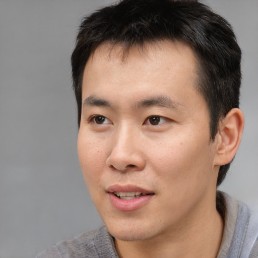 Joyful asian young-adult male with short  brown hair and brown eyes