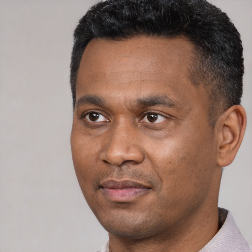 Joyful black young-adult male with short  black hair and brown eyes