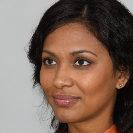 Joyful black young-adult female with long  brown hair and brown eyes