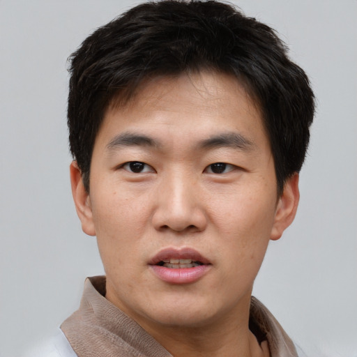 Joyful asian young-adult male with short  brown hair and brown eyes