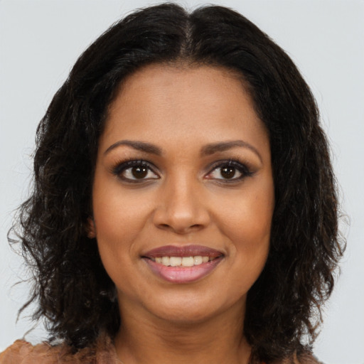 Joyful black young-adult female with long  brown hair and brown eyes