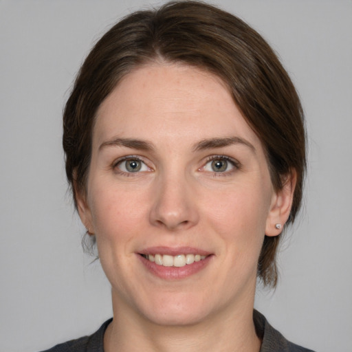 Joyful white young-adult female with medium  brown hair and grey eyes