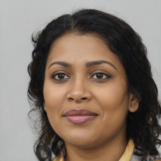 Joyful black young-adult female with long  brown hair and brown eyes