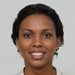 Joyful black young-adult female with short  black hair and brown eyes