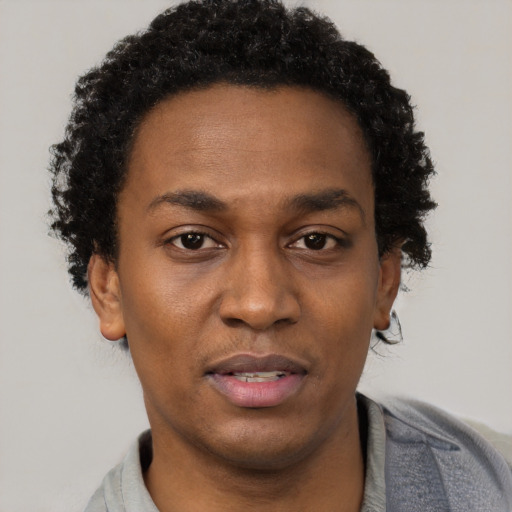 Joyful black young-adult male with short  brown hair and brown eyes