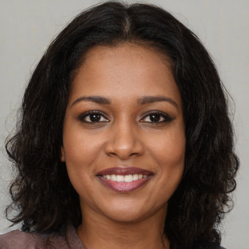 Joyful black young-adult female with long  brown hair and brown eyes