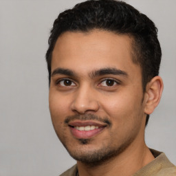 Joyful latino young-adult male with short  black hair and brown eyes