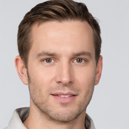 Joyful white young-adult male with short  brown hair and grey eyes