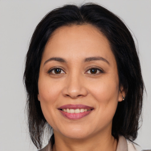 Joyful latino adult female with medium  brown hair and brown eyes