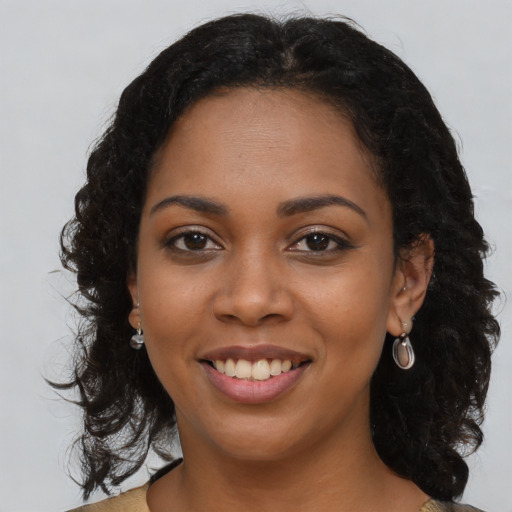 Joyful black young-adult female with long  brown hair and brown eyes