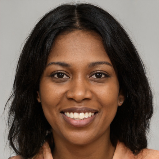 Joyful black young-adult female with long  black hair and brown eyes