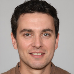 Joyful white young-adult male with short  brown hair and grey eyes