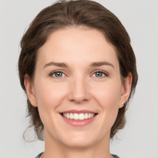 Joyful white young-adult female with medium  brown hair and grey eyes