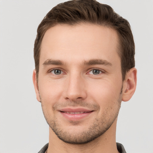 Joyful white young-adult male with short  brown hair and grey eyes