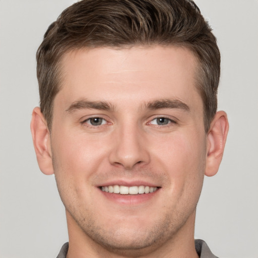 Joyful white young-adult male with short  brown hair and grey eyes