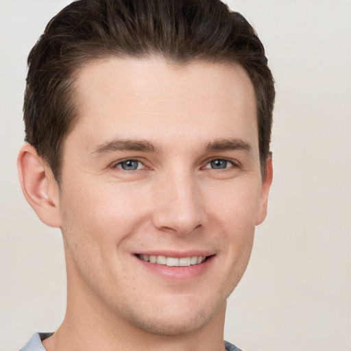 Joyful white young-adult male with short  brown hair and grey eyes