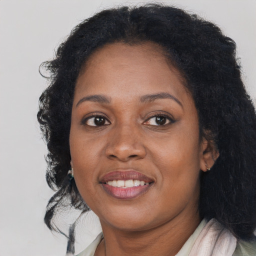 Joyful black young-adult female with long  brown hair and brown eyes