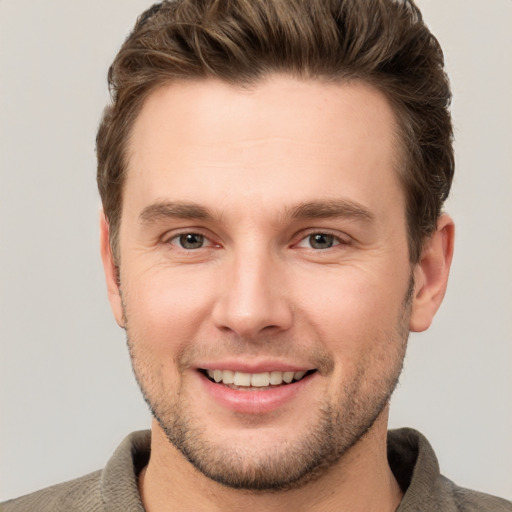 Joyful white young-adult male with short  brown hair and grey eyes