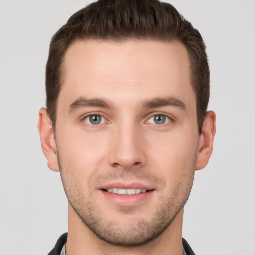 Joyful white young-adult male with short  brown hair and grey eyes