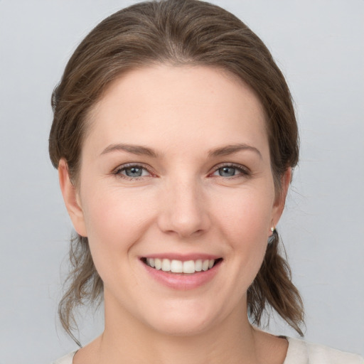 Joyful white young-adult female with medium  brown hair and grey eyes