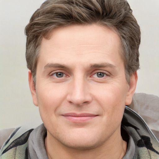 Joyful white young-adult male with short  brown hair and grey eyes