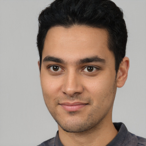 Joyful latino young-adult male with short  black hair and brown eyes