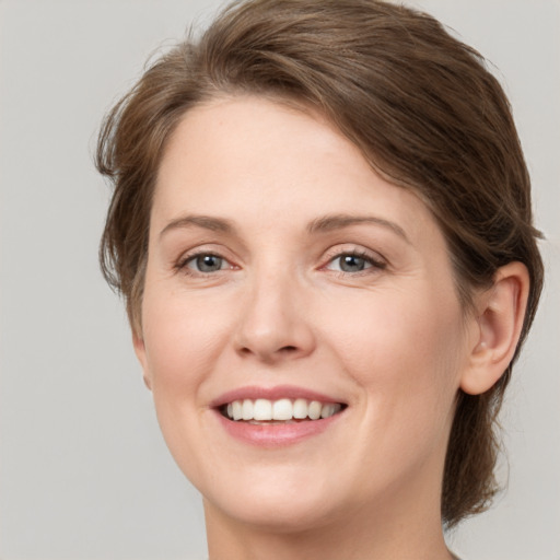 Joyful white young-adult female with medium  brown hair and grey eyes