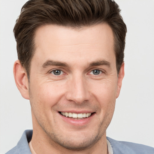 Joyful white young-adult male with short  brown hair and grey eyes