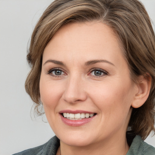 Joyful white adult female with medium  brown hair and grey eyes