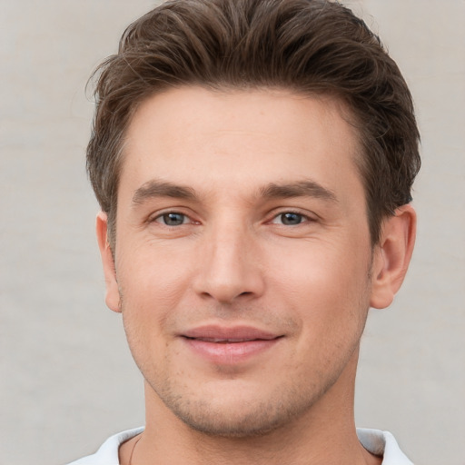 Joyful white young-adult male with short  brown hair and grey eyes