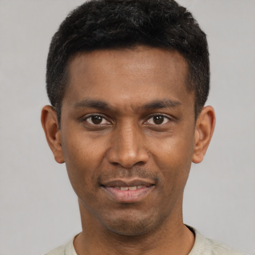 Joyful black young-adult male with short  black hair and brown eyes
