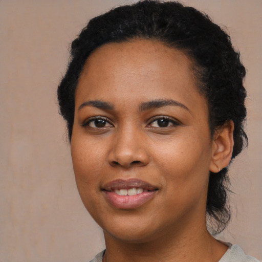 Joyful black young-adult female with long  brown hair and brown eyes