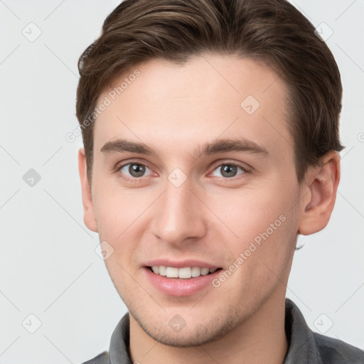 Joyful white young-adult male with short  brown hair and grey eyes