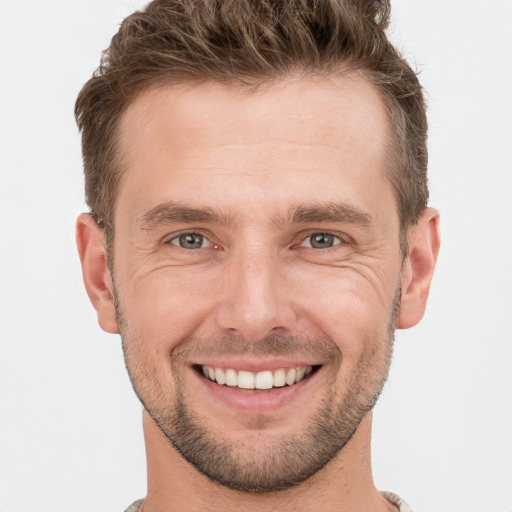 Joyful white young-adult male with short  brown hair and grey eyes