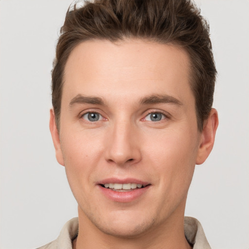 Joyful white young-adult male with short  brown hair and grey eyes